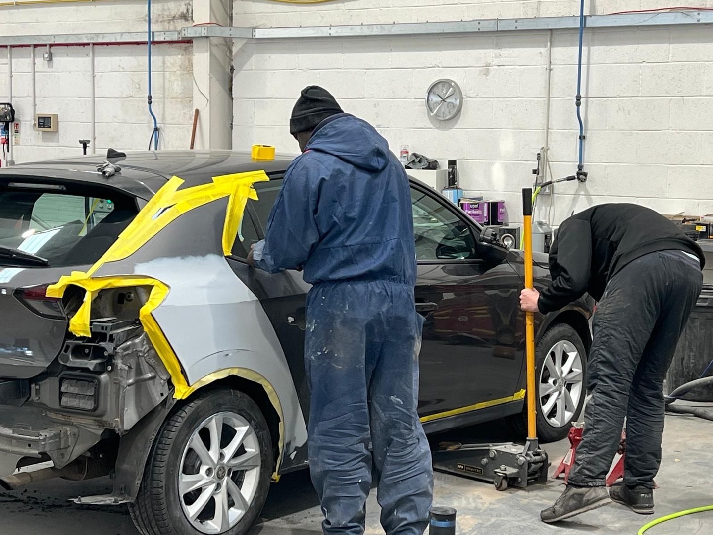 Workshop process shot showing vehicle panel prep and masking